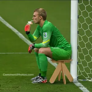 Goalkeeper relaxing in a stool next to goal post drinking juice